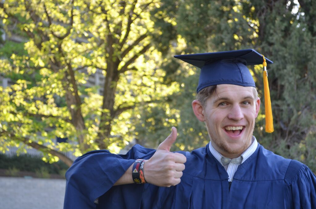 College graduate in cap and gown giving a "thumbs up"