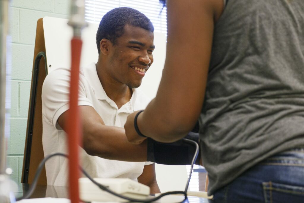 Teen practices using a blood pressure cuff.